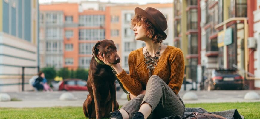 a woman sitting in an outdoor grass patch with her dog